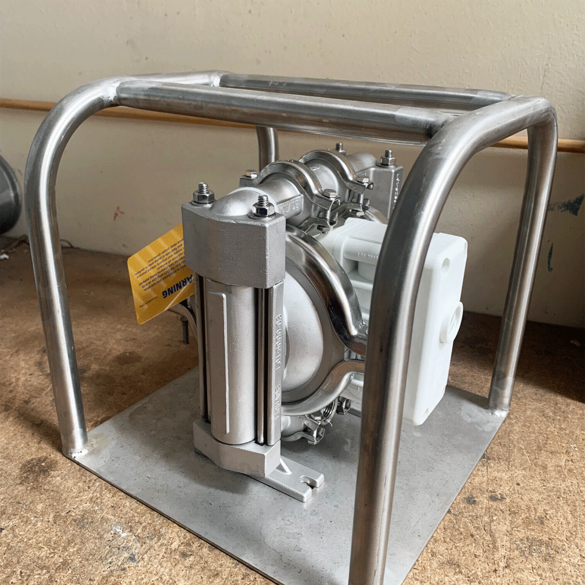 A Graco stainless steel pump positioned atop a robust metal frame, highlighting its durable construction and design.